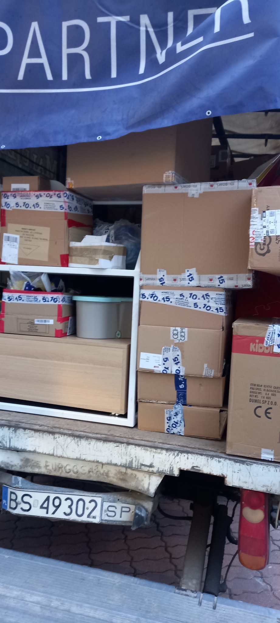 Wnętrze ciężarówki wypełnione kartonami i meblami podczas przeprowadzki, widoczny numer rejestracyjny pojazdu BS 49302 SP oraz baner z napisem PARTNER