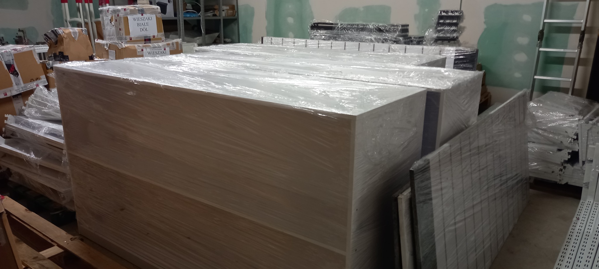 Spakowane meble w folii stretch, przygotowane do transportu w Suwałkach, widoczne także kartony z akcesoriami.