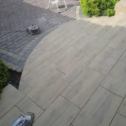 Ułożona, drewnopodobna terakota na schodach i tarasie w Sułkowicach, widoczne narzędzia glazurnicze i zwinięty przedłużacz, w tle drabina i skrzynka narzędziowa.