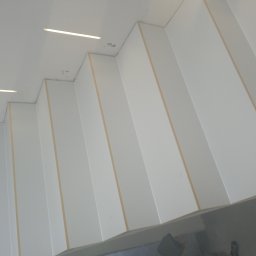 Bartłomiej Błaszkowski - Nowoczesny sufit z białych paneli z wbudowanym oświetleniem LED, widok pod kątem.