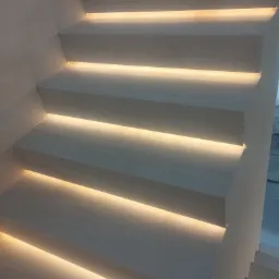 Nowoczesne schody z podświetleniem LED wbudowanym pod każdym stopniem, tworzące ciepłą, dekoracyjną iluminację.