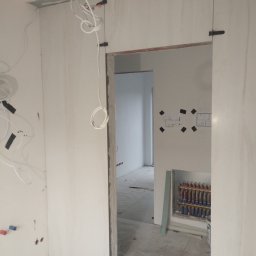 Bartłomiej Błaszkowski - Montaż płyt karton gipsowych w łazience, widoczne przewody elektryczne i schemat instalacji na ścianie.