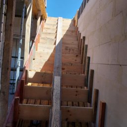 Wojtek - Szczegółowe ujęcie szalunku drewnianego schodów w trakcie budowy domu murowanego, widoczne bloczki betonowe i stalowe podpory.