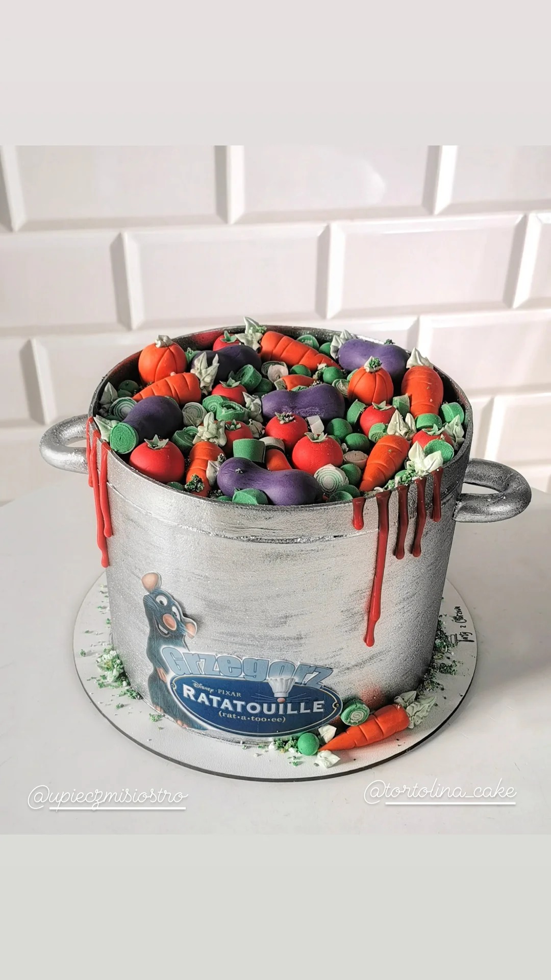 Tort w kształcie srebrnego garnka z warzywami z bajki Ratatuj, dekorowany lukrem imitującym sos pomidorowy.