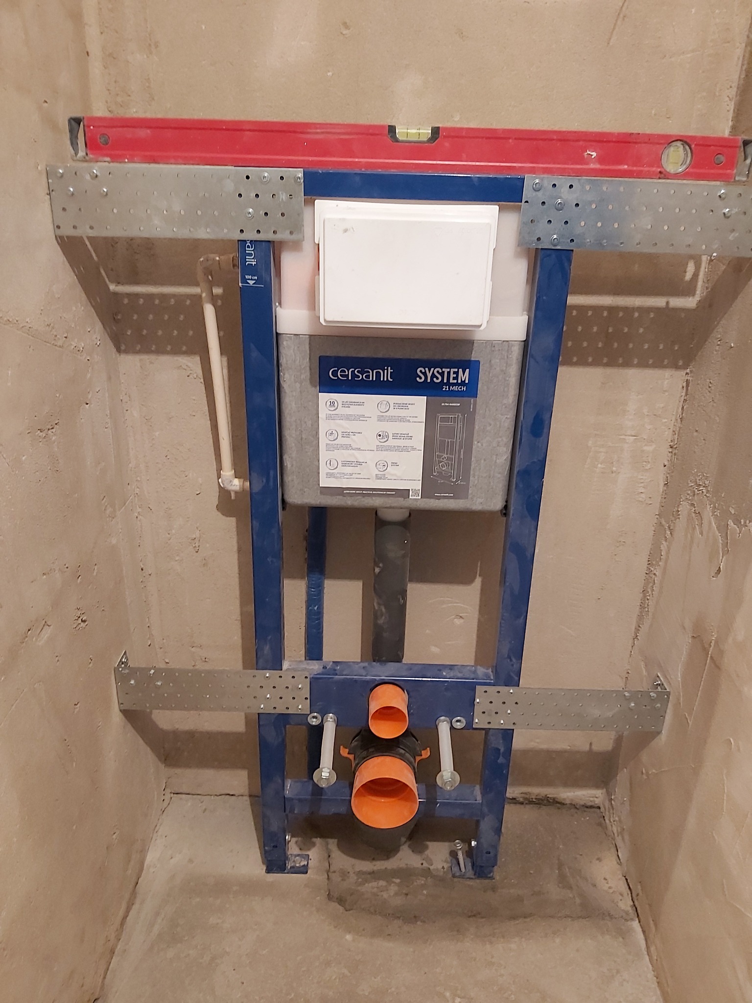 Stelaż podtynkowy Cersanit System 21 Mech zamontowany w surowej łazience, poziomica na górnej belce, widoczne rury kanalizacyjne.