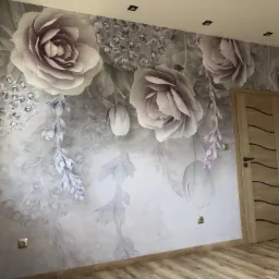 Ściana z fototapetą w kwiaty w odcieniach szarości i fioletu, drewniane panele podłogowe, jasne drzwi z ciemnymi wstawkami.