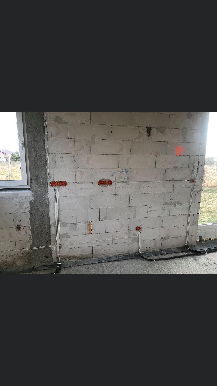 Instalacja elektryczna w surowym budynku w Świdnicy: widoczne kable prowadzone po ścianach z betonu komórkowego oraz puszki instalacyjne pod gniazdka i włączniki.