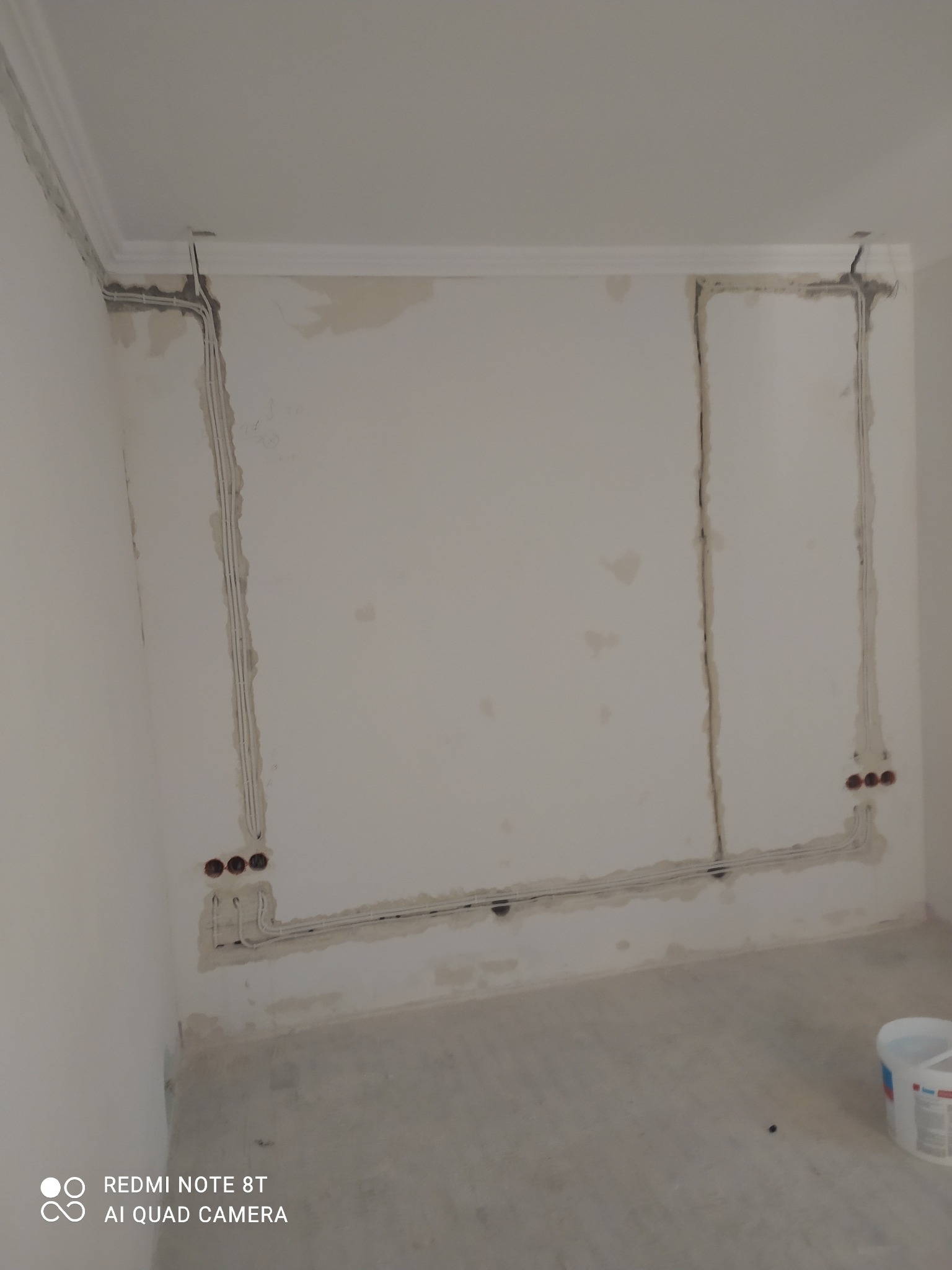 Przygotowanie ścian do wykończenia: widoczne bruzdy z przewodami elektrycznymi, gładź na ścianach przed dalszymi pracami, listwa dekoracyjna pod sufitem.