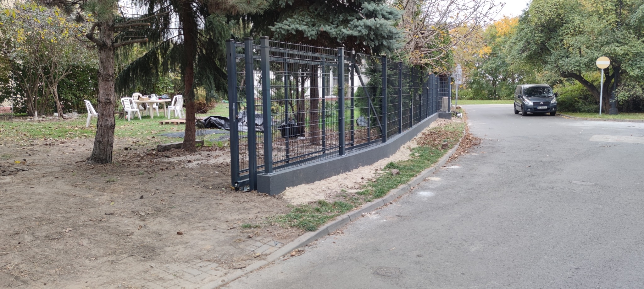 Nowoczesne ogrodzenie panelowe w Makowie Mazowieckim, widoczne z perspektywy ulicy, z elementami zieleni w tle i samochodem w oddali.