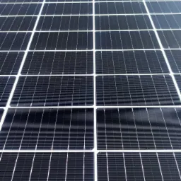 Zamontowane panele słoneczne na dachu, widoczne z bliska, regularny układ z białymi ramami.