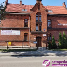 Indywidualna Praktyka Lekarska Karol Busz ortopeda.elk.pl - Fasada budynku ortopedii z szyldem 'ortopeda.elk.pl', numerem 19 i napisem 'HOTELIK' na tle błękitnego nieba. Widoczny chodnik i fragment ulicy.