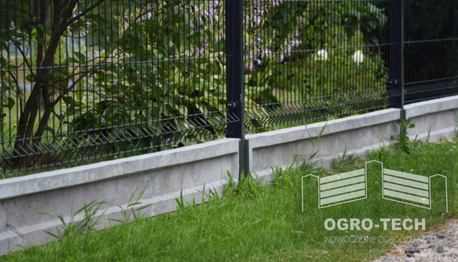Fragment ogrodzenia panelowego z podmurówką betonową, widoczne trawa i zieleń w tle, logo firmy w prawym dolnym rogu.