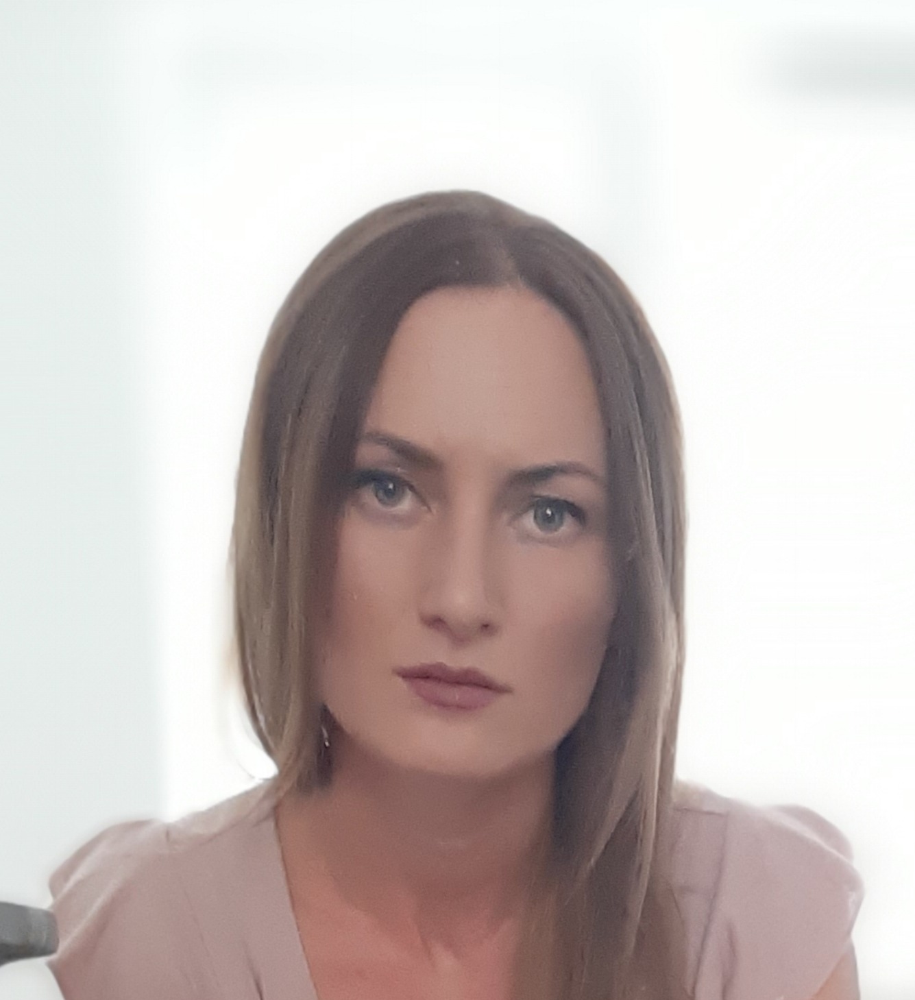 Portret kobiety o jasnej karnacji i brązowych włosach, spoglądającej wprost, z delikatnym makijażem.