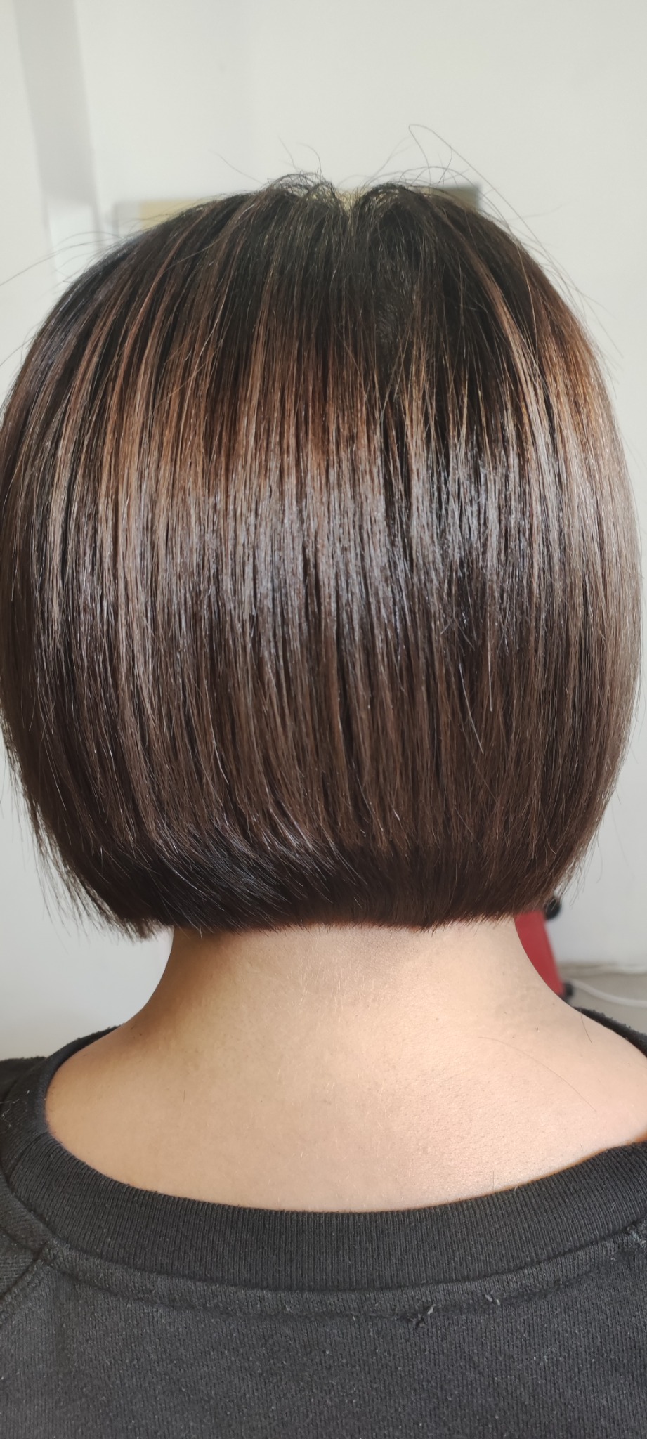 Krótkie, brązowe włosy z refleksami, widok z tyłu, świeżo po strzyżeniu, z delikatnym połyskiem.