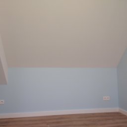 RomArt (Set-Kom) - Pokój na poddaszu po remoncie: błękitne ściany, biały sufit ze skosem, drewnopodobna podłoga, białe listwy przypodłogowe i podwójne gniazdka elektryczne na ścianie.