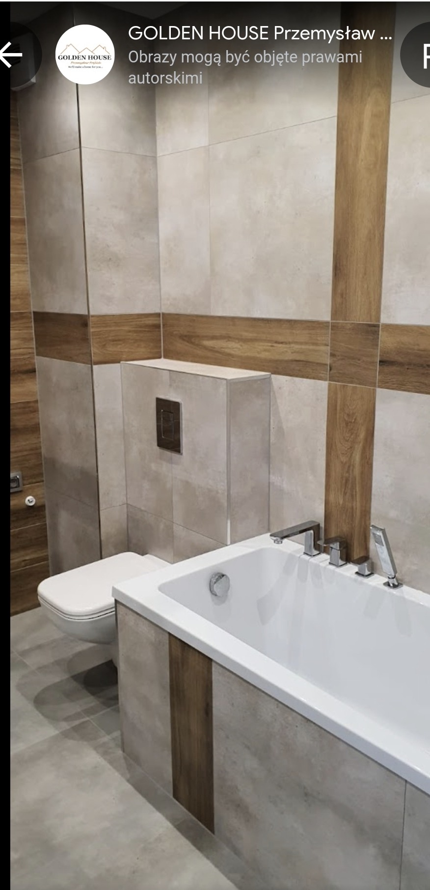 Nowoczesna łazienka z wanną obudowaną płytkami imitującymi beton i drewno, wisząca toaleta z ukrytym systemem spłukiwania, chromowana bateria wannowa z deszczownicą.