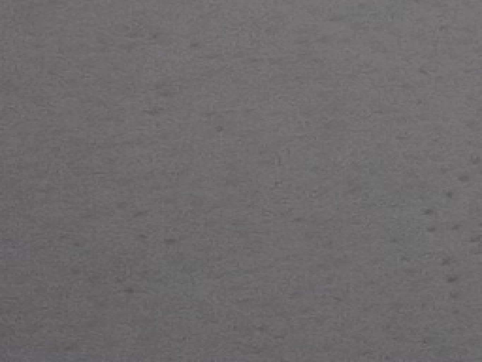 Jednolita, szara, matowa powierzchnia z delikatną teksturą, przypominająca świeżo nałożony tynk lub farbę.
