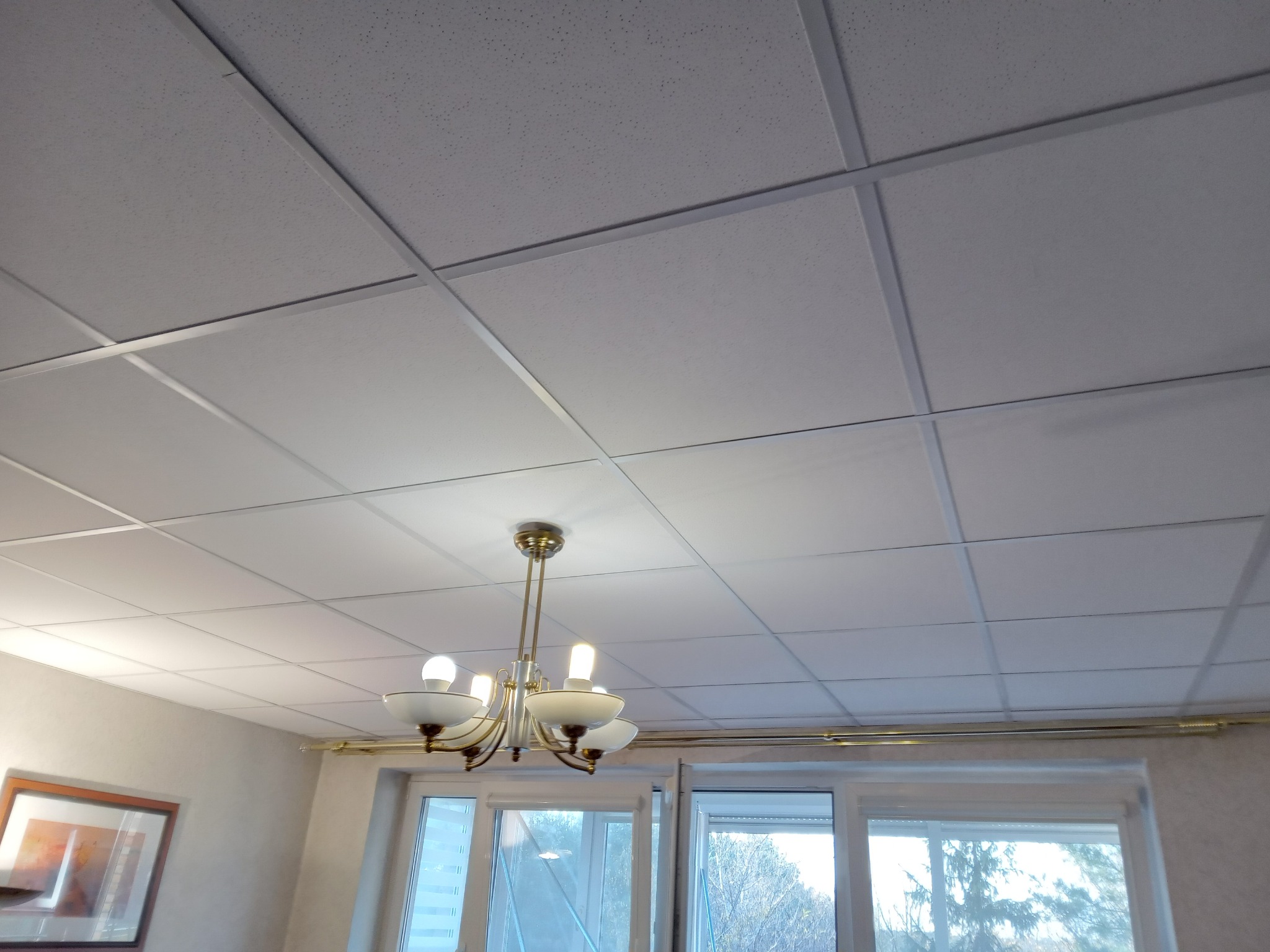 Sufit podwieszany kasetonowy z widoczną lampą wiszącą w pomieszczeniu z oknem.