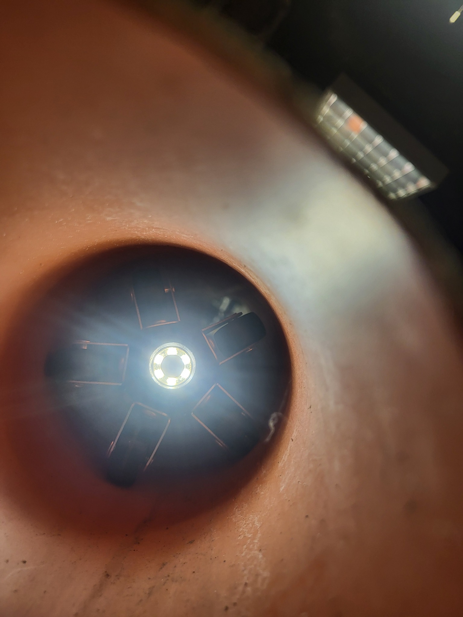 Wnętrze pomarańczowej rury kanalizacyjnej oświetlone od wewnątrz lampą inspekcyjną z widocznymi elementami blokady.