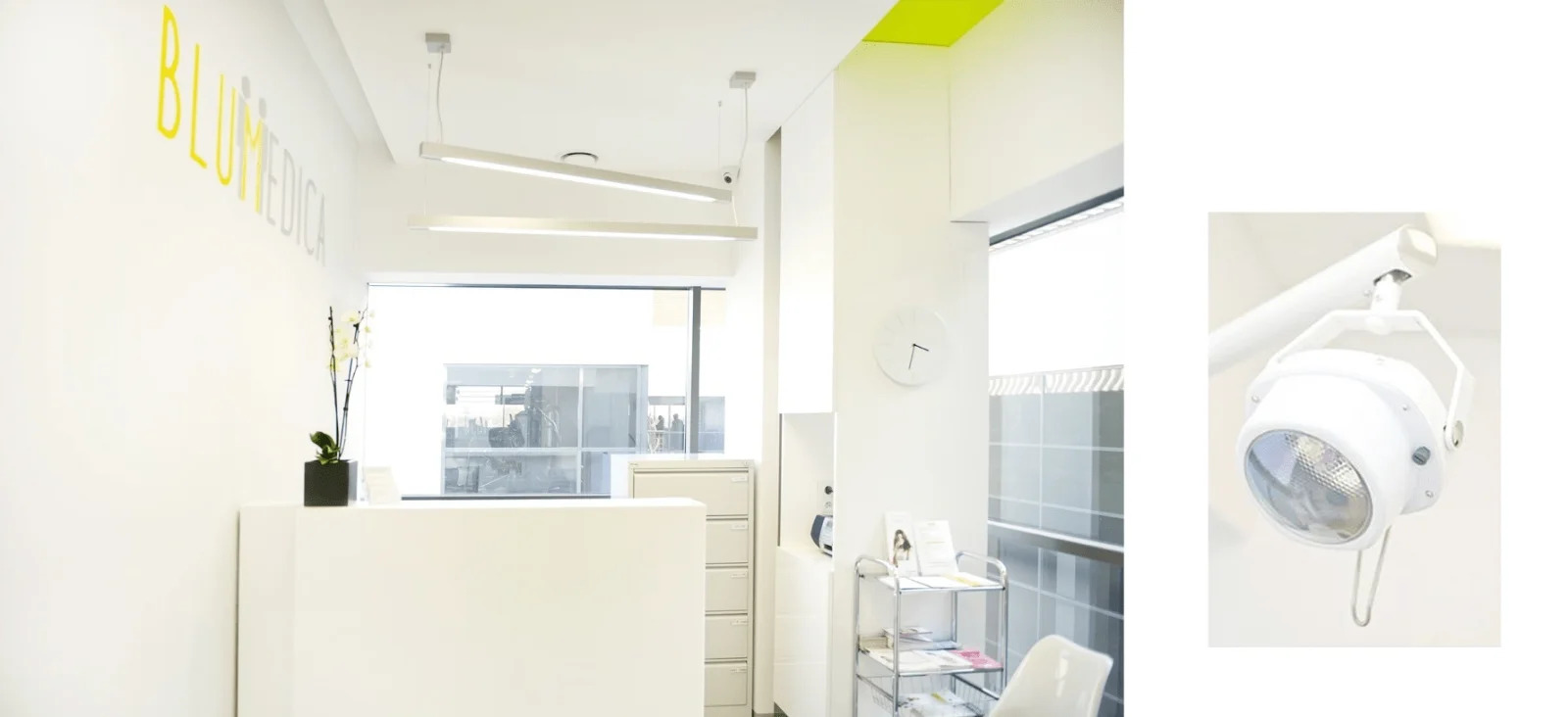 Jasne wnętrze gabinetu lekarskiego z recepcją, lampami sufitowymi i lampą zabiegową po prawej stronie