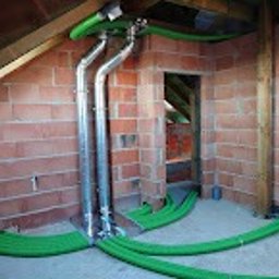 BCS Sp. z o.o. - System kanałów wentylacyjnych z zielonymi rurami w surowym wnętrzu poddasza z ceglanymi ścianami i drewnianą konstrukcją dachu.