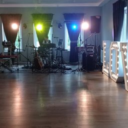 Cinnamon Live Cover Band - Sala weselna przygotowana na przyjęcie z podświetlanymi literami LOVE, rozstawionym sprzętem muzycznym: perkusja, gitara, keyboard, kolumny nagłośnieniowe, oświetlenie sceniczne.