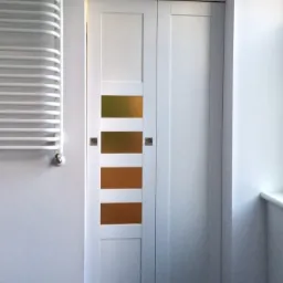 Białe dwuskrzydłowe drzwi z czterema poziomymi przeszkleniami w odcieniach brązu i złota, zamontowane w białej ścianie, obok grzejnika drabinkowego.