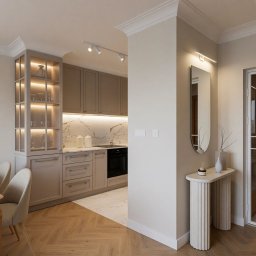 Dizaro Studio Projektowania Wnętrz - Elegancka kuchnia w odcieniach beżu i bieli, z marmurowym blatem i podświetlaną witryną. Parkiet w jodełkę przechodzi w marmurową posadzkę. Lustro i konsola przy wejściu.