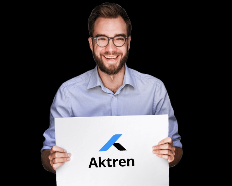 Uśmiechnięty mężczyzna w okularach trzymający białą kartkę z logo 'Aktren' na czarnym tle.
