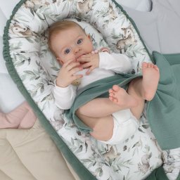 TOLO Sp. z o.o. - Niemowlę leżące w kokonie z motywem leśnych zwierząt, otulone zielonym kocykiem. Widoczny fragment kołderki w beżowym kolorze.