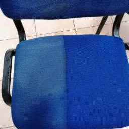 Częściowo wyczyszczone, błękitne krzesło biurowe z widoczną r&oacute;żnicą w kolorze tapicerki, ukazujące efekt czyszczenia.