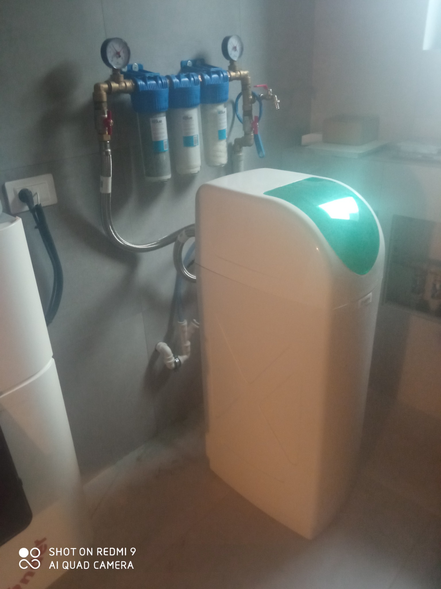 Zmiękczacz wody z trzema filtrami wstępnymi podłączony do instalacji wodnej, widoczne manometry i zawory odcinające.