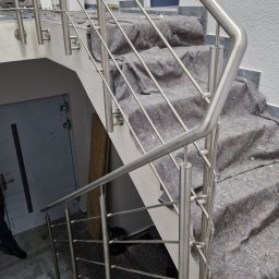 Mariusz Cierlik - Nowoczesne schody z marmurowymi stopniami i balustradą ze stali nierdzewnej, zabezpieczone materiałem ochronnym podczas prac wykończeniowych.