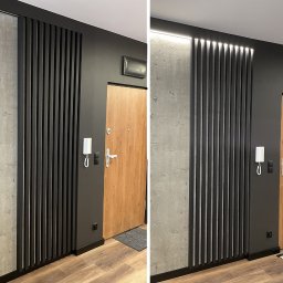 I WOOD DESIGN - Nowoczesny przedpokój z drewnianymi lamelami w kolorze czarnym, zamontowanymi na ścianie z surowego betonu. Po prawej stronie widoczne drzwi wejściowe z jasnego drewna i domofon. Na drugim ujęciu...