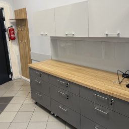 I WOOD DESIGN - Szara szafka z drewnianym blatem i białymi szafkami wiszącymi, widoczne klucze w zamkach szuflad, na tle ściany z wieszakiem i gaśnicą.