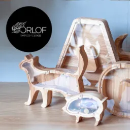 Ręcznie robione drewniane skarbonki w kształcie kota, świnki i domku, z przezroczystymi ściankami, prezentujące logo firmy na czarnym tle.