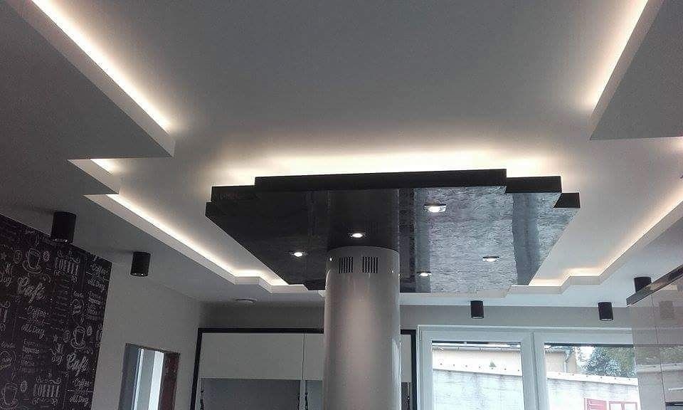 Sufit podwieszany z oświetleniem LED w nowoczesnej kuchni, z czarnymi elementami dekoracyjnymi i centralną kolumną wentylacyjną.