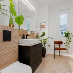 Nowoczesna łazienka z geometrycznymi płytkami na ścianach i podłodze, białą umywalką na czarnej szafce, roślinami doniczkowymi i krzesłem z pomarańczowym siedziskiem.