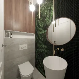 Nowoczesna łazienka z wiszącą toaletą, umywalką wolnostojącą i czarno-zieloną tapetą w liście, oświetlona trzema wiszącymi lampami z elementami w kolorze złotym.