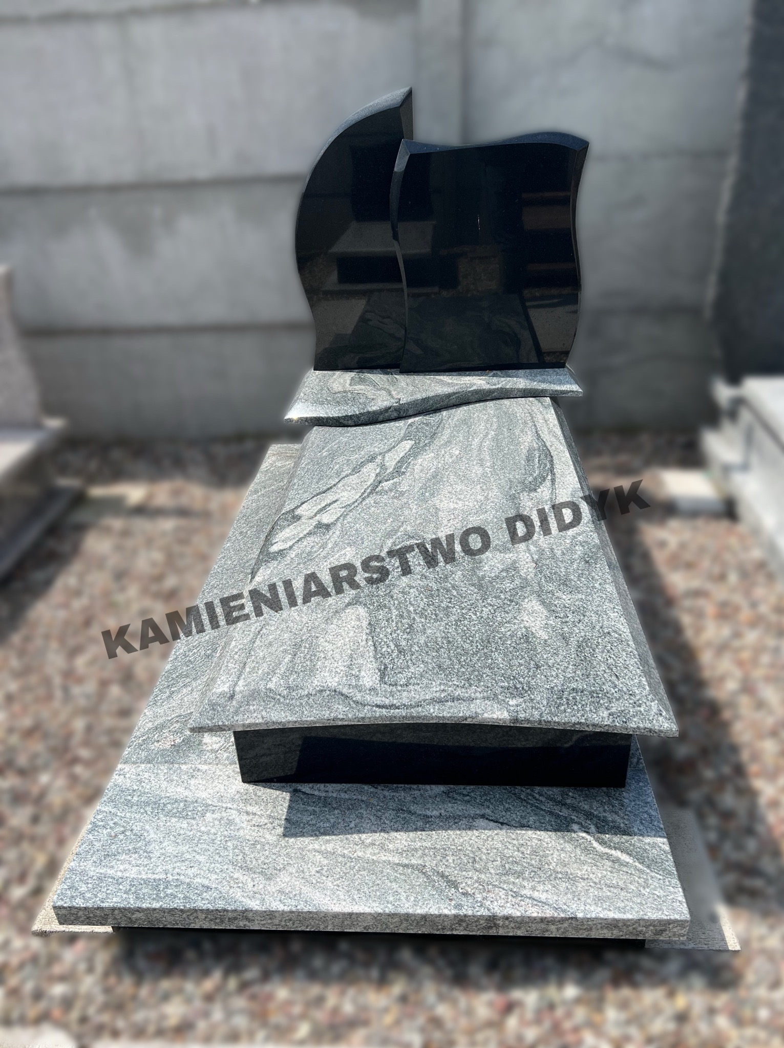 Nowoczesny nagrobek z szarego granitu z czarnymi elementami, polerowany, z widocznym napisem 'KAMIENIARSTWO DIDYK'.