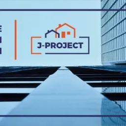 Niski kąt widzenia na nowoczesny budynek biurowy z logo J-Project, podkreślający projektowanie konstrukcji budowlanych.