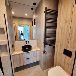 Usługi Budowlane MatBud Mateusz Malec - Nowoczesna łazienka z umywalką nablatową, grzejnikiem drabinkowym i toaletą. Uwagę zwraca lustro z widocznym odbiciem osoby robiącej zdjęcie.