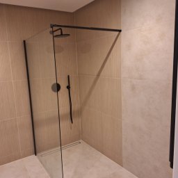 Usługi Budowlane MatBud Mateusz Malec - Nowoczesna kabina prysznicowa z czarnymi detalami na tle beżowych płytek. Minimalistyczny design, widoczny odpływ liniowy. Ukończona realizacja.