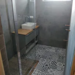 Nowoczesna łazienka z szarą glazurą ścienną, kabiną prysznicową ze szkła i wzorzystą podłogą z płytek w stylu patchwork