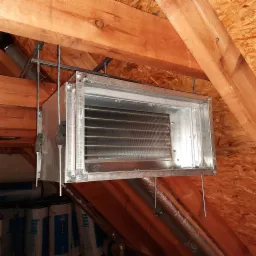 Centrala wentylacyjna z rekuperacją zamontowana pod drewnianym stropem na poddaszu we Wrocławiu, widoczne rury wentylacyjne i ocieplenie.