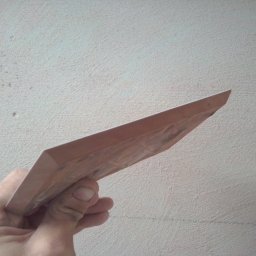 J.S.Project - Szpachelka w dłoni na tle surowej, szarej ściany z widocznymi nierównościami i śladami po poprzednich pracach.