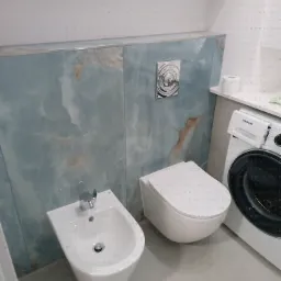 Nowoczesna łazienka z bidetem, toaletą i pralką Samsung, wykończona płytami imitującymi marmur w odcieniach błękitu i beżu. Minimalistyczny design.