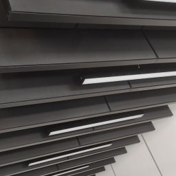 Grzegorz Smoleński - Szary sufit rastrowy z liniowymi oprawami oświetleniowymi LED, widok pod kątem.