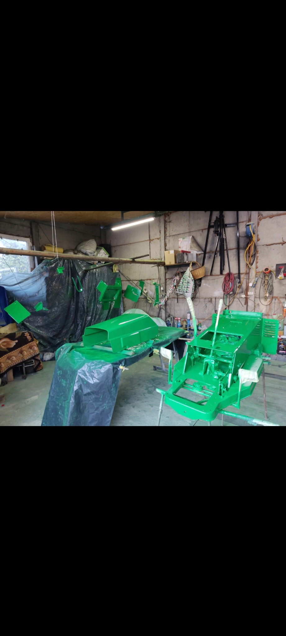 Elementy konstrukcyjne pomalowane na jaskrawy zielony kolor, suszone w warsztacie. Widoczne detale ramy i karoserii, przygotowane do dalszego montażu.