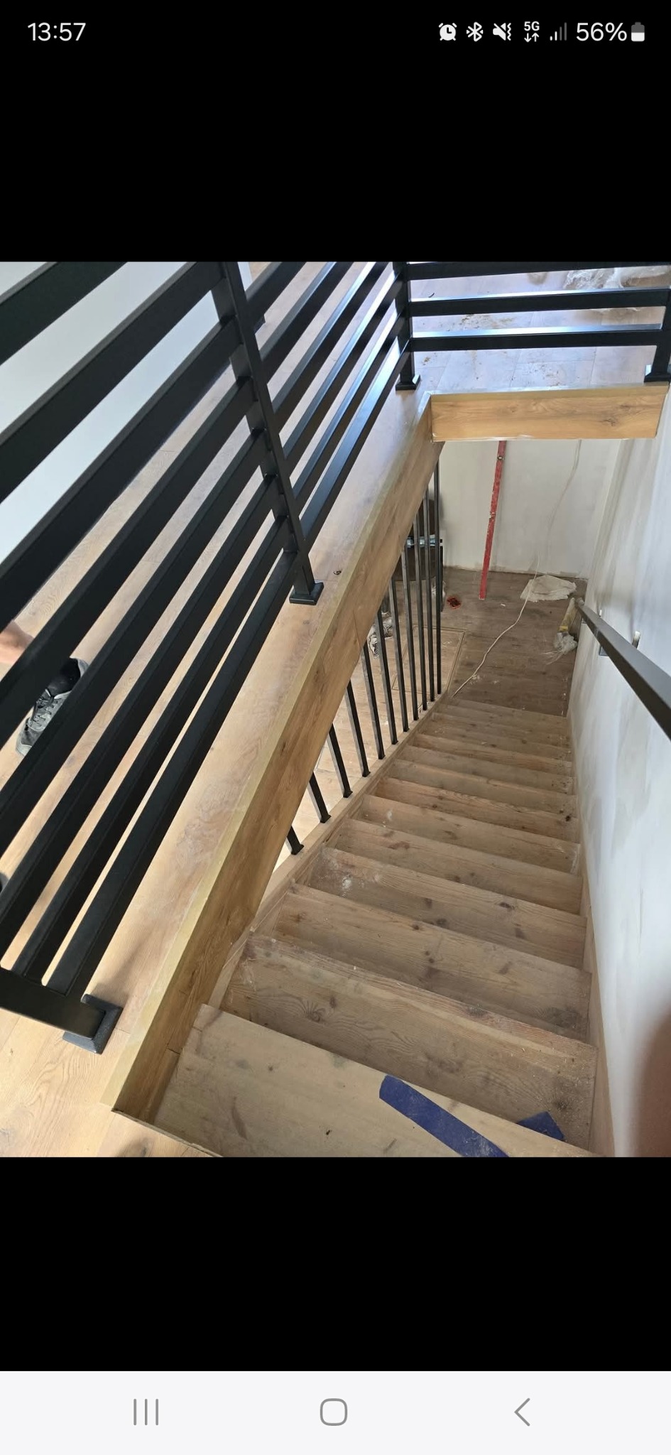 Schody drewniane z metalową balustradą w nowoczesnym stylu, widok z góry, jasne drewno, czarne elementy metalowe.